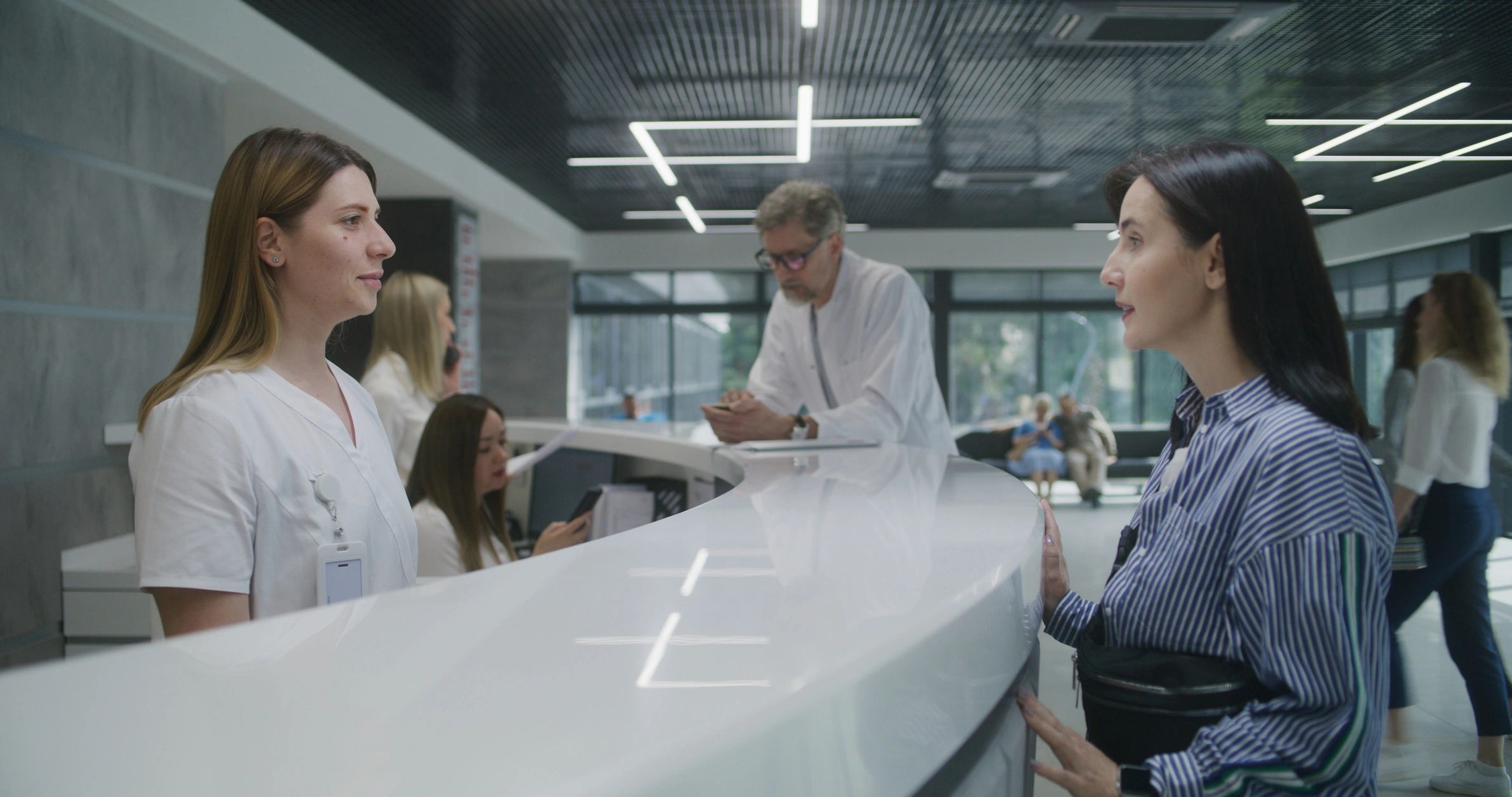 Person speaking with staff at a reception desk