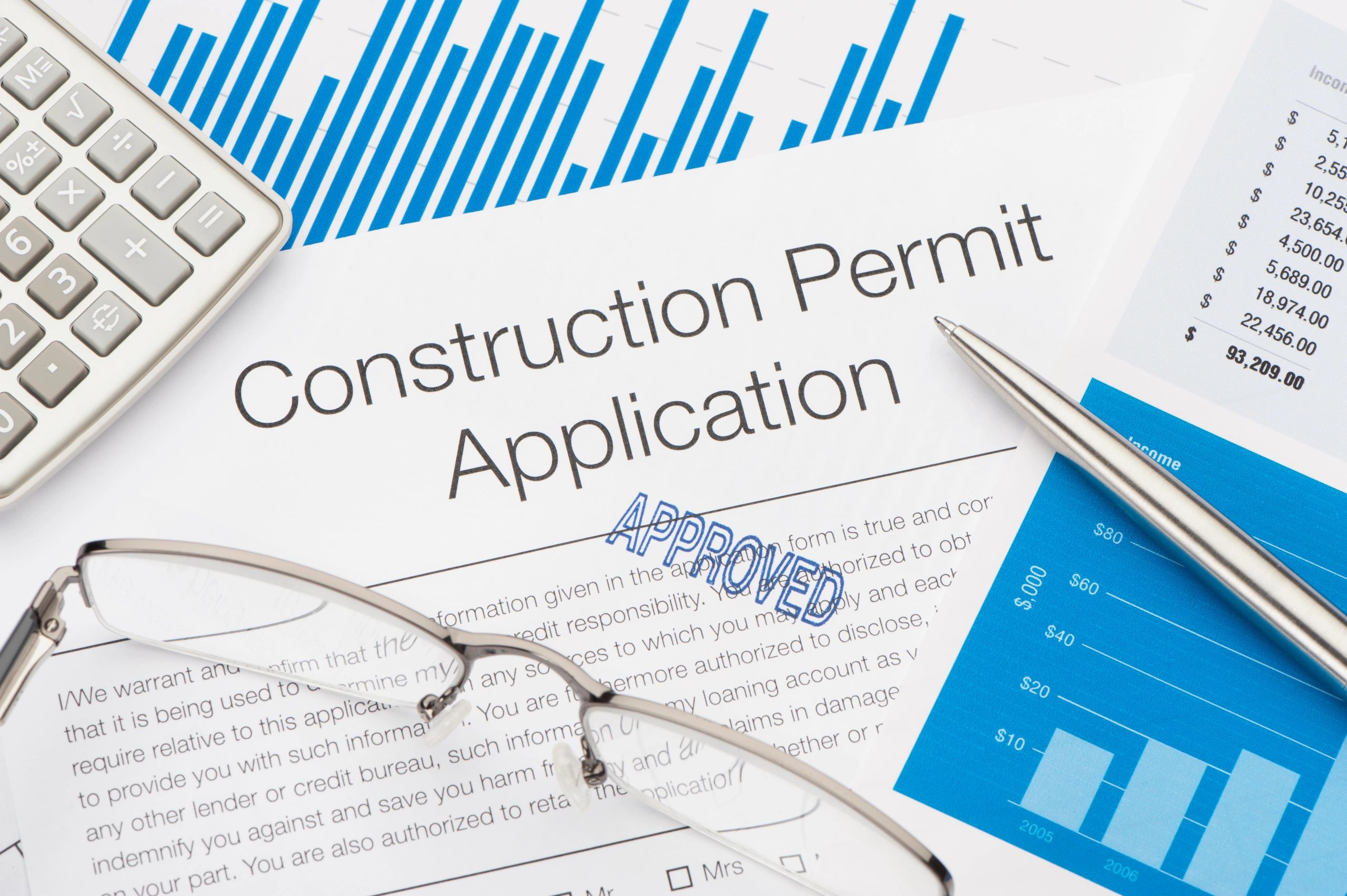 Approved permit application with pen and calculator