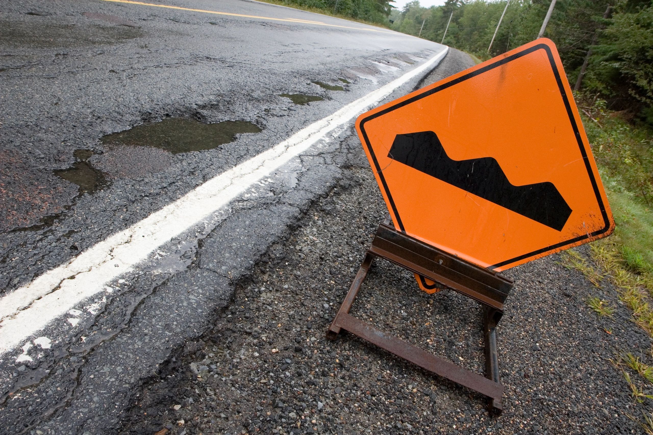 Road warning sign beside a rough road
